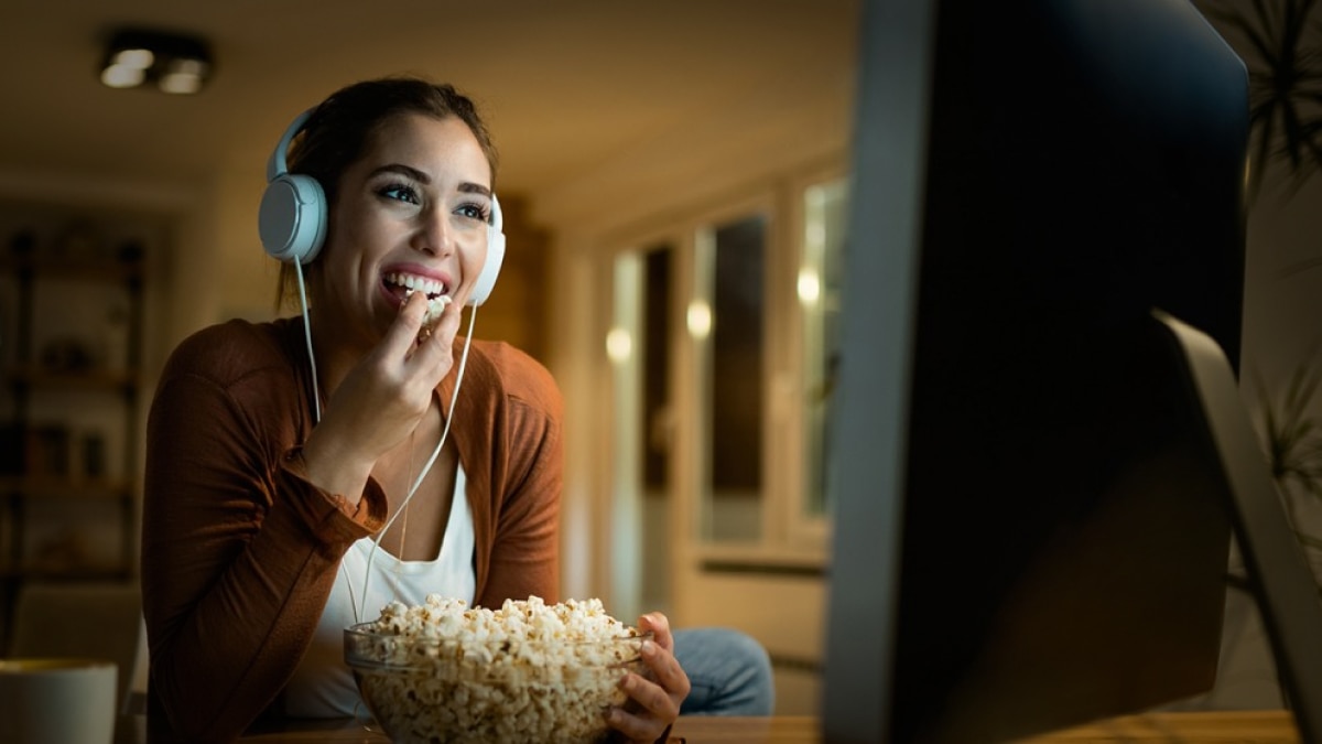 woman eating popcorn looking at computer screen